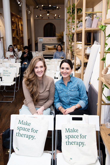 Image of two women sitting next to each other smiling. 