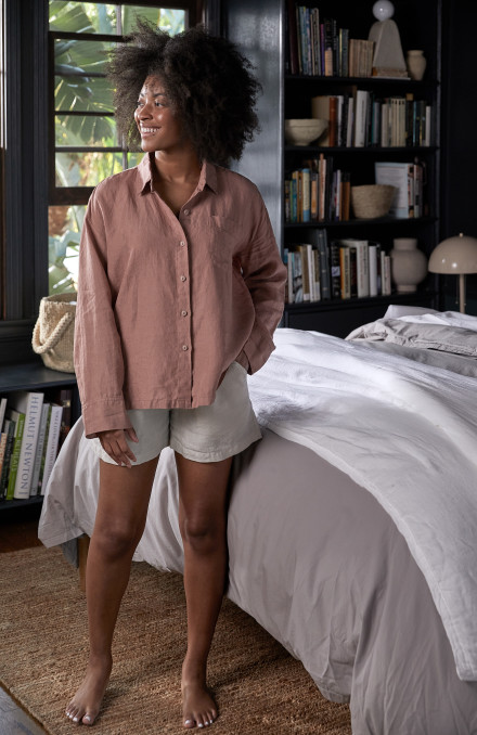 Woman standing in her room wearing a bone linen short and clay linen top