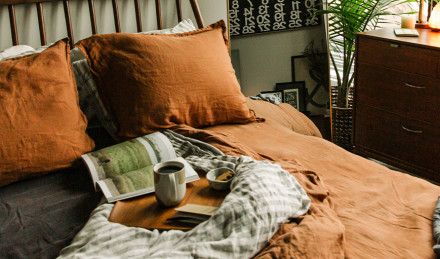 Bed with a cup of coffee and a magazine sitting on it. 
