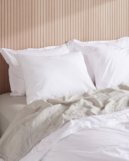 A bed with white and bone linen sheets