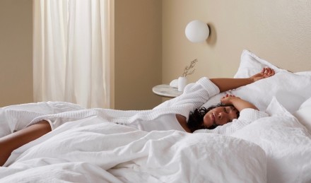 Woman in white linen bed napping.