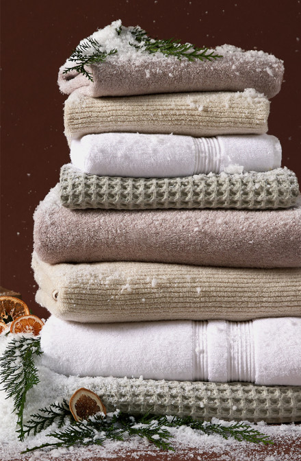 A festive stack of towels in various colors and textures against a deep red background