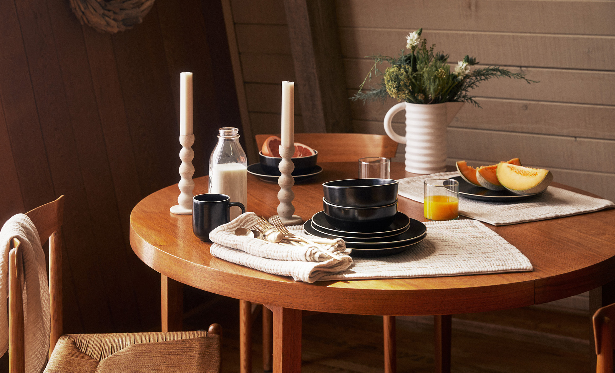Round wood table with various plates, vases, and candlesticks in a cozy wood cabin