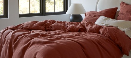 A messy bed with cream and canyon-red linen sheets