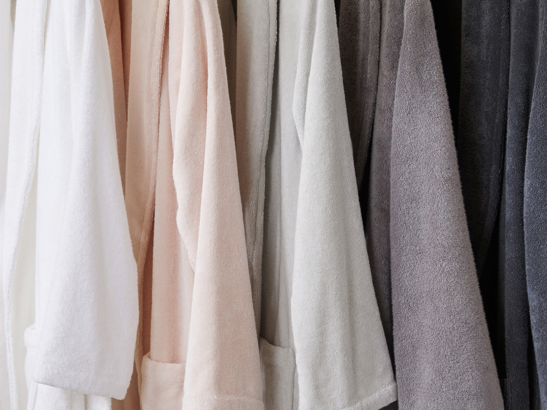 White, blush, mineral, stone, and dusk robes hanging side by side