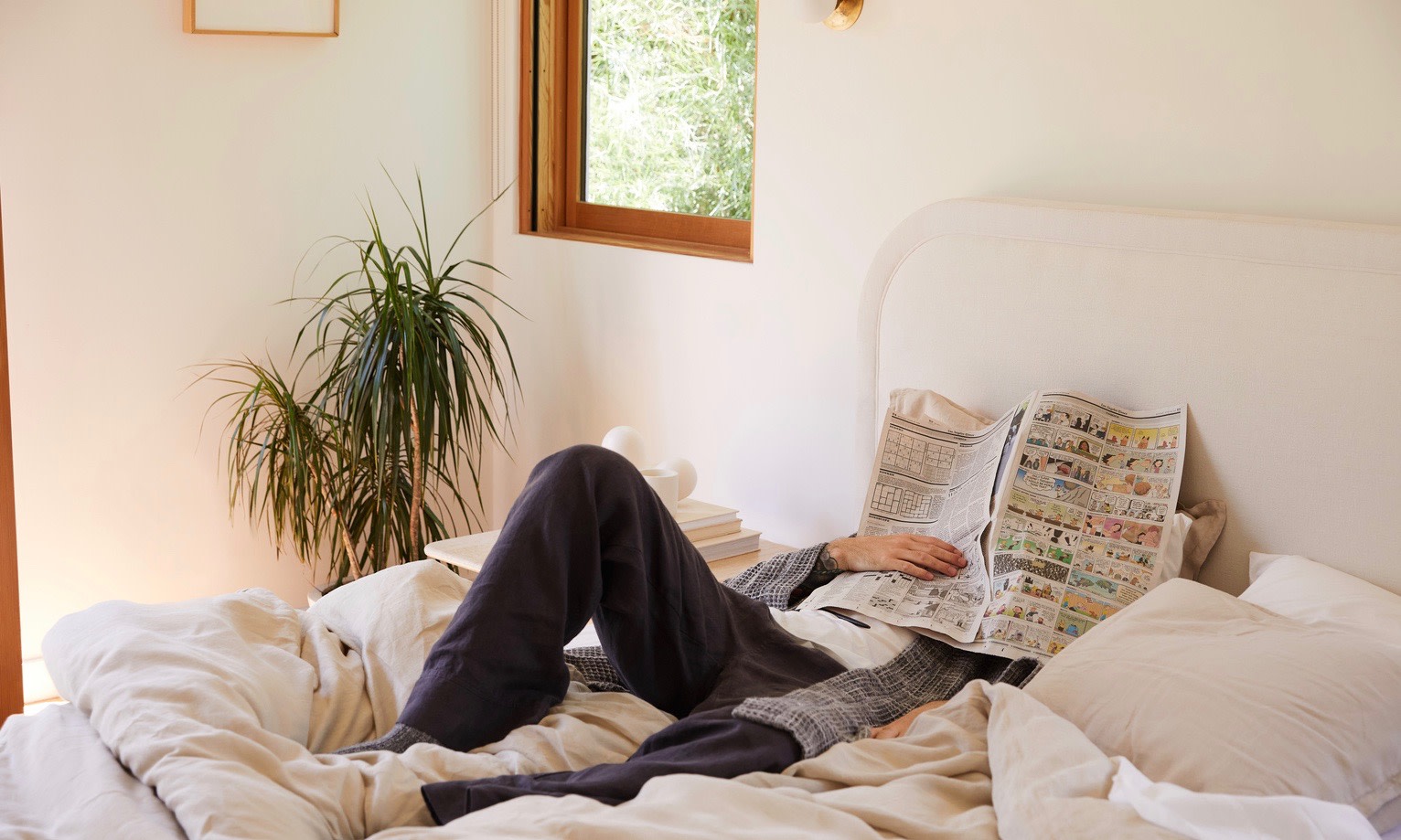 Man in bed with newspaper. 