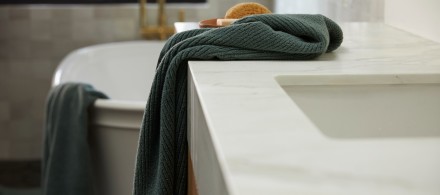 An agave soft rib towel hanging over the edge of a marble bathroom counter