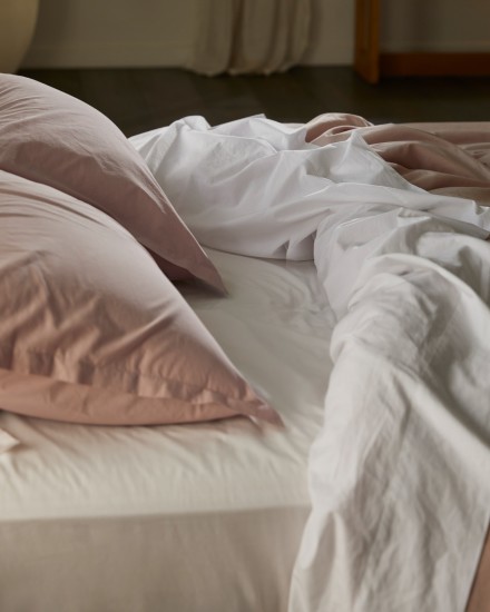 A bed with white and haze cotton percale sheets