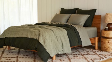 A cozy bed with moss and evergreen linen sheets and blankets