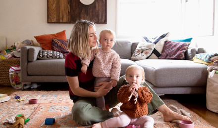 Image of woman with her two babies in knit sweaters. 