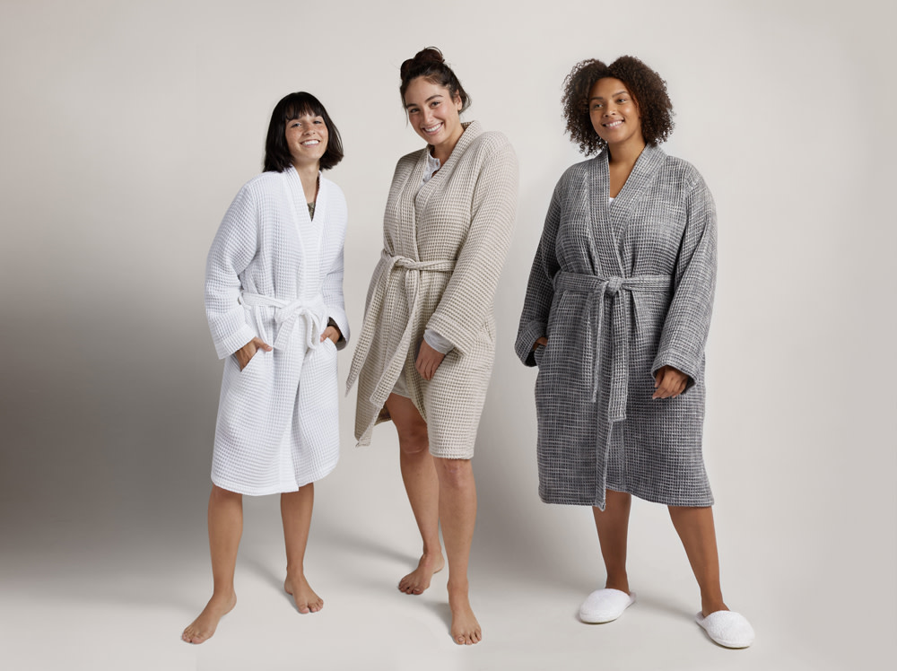 Three women standing next to each other in waffle robes.