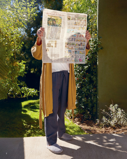 Person standing outside in their robe reading the newspaper
