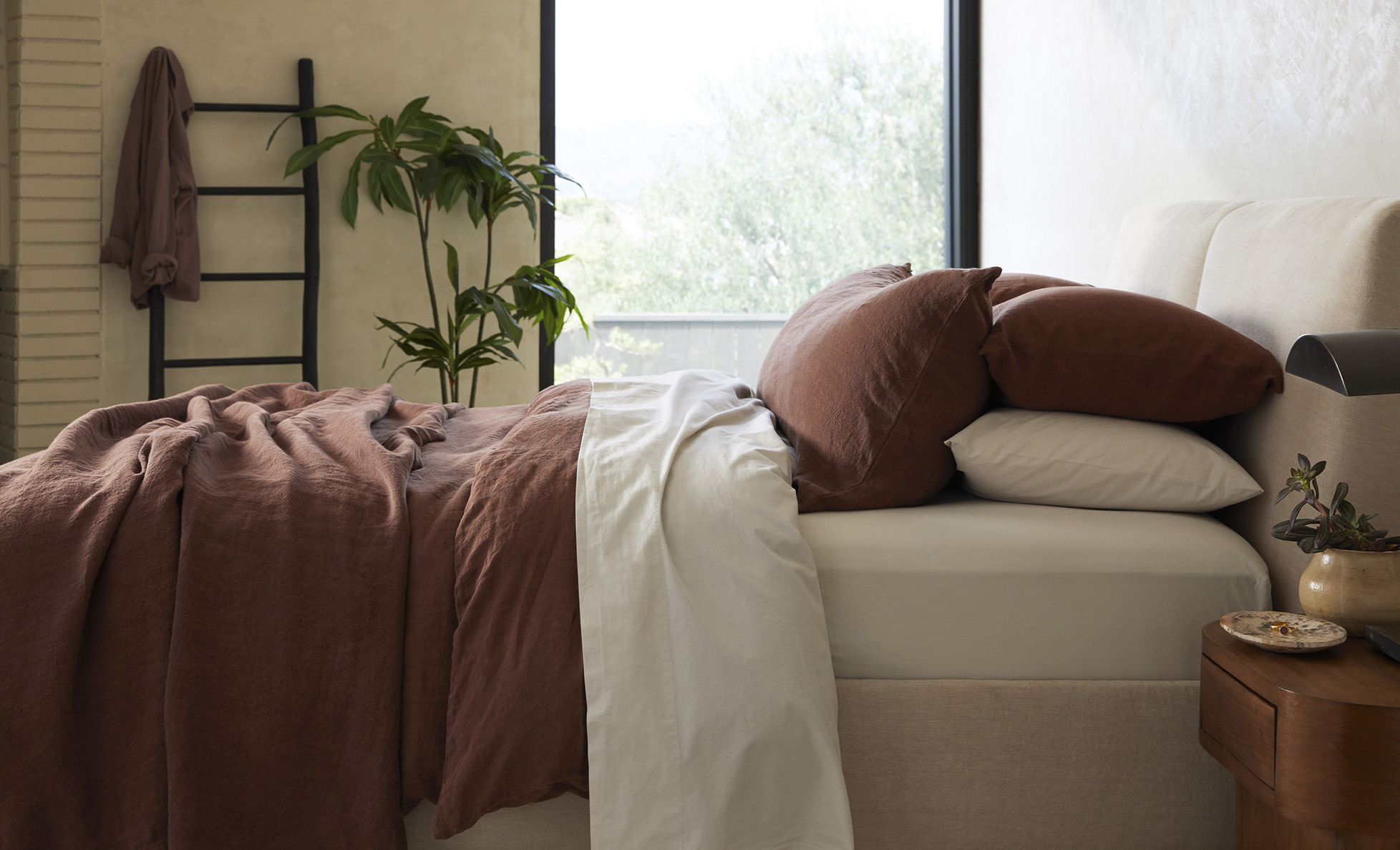 A neatly made bed with warm brown linen sheets