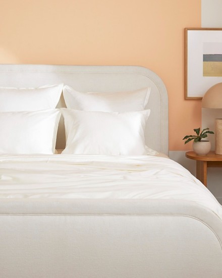 A neat bed with cream sateen sheets