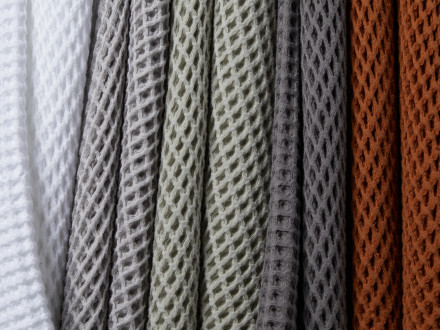 White, light grey, willow, charcoal, and terra waffle towels hanging in a row