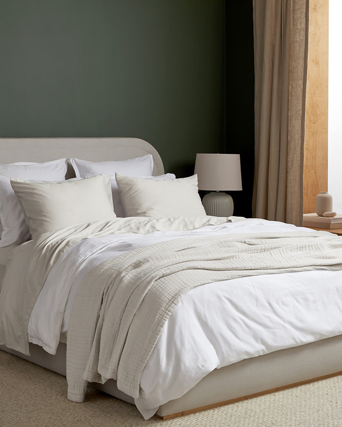 A neat bed with white and cream brushed cotton sheets