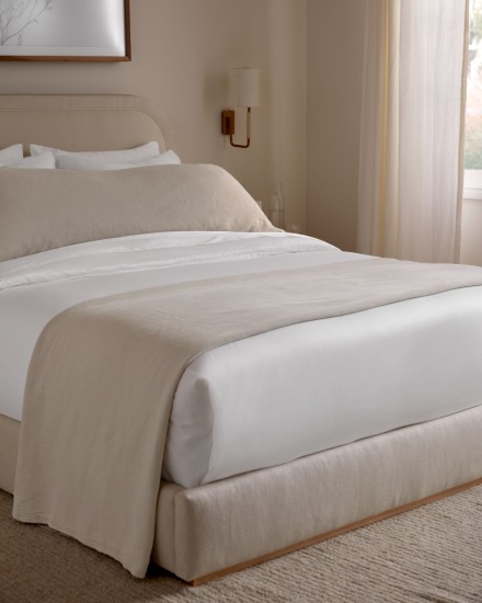 A neatly made bed with white and beige sheets