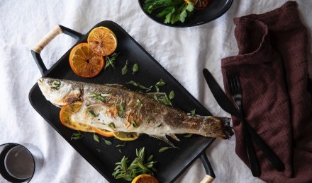 Branzino with citrus and herbs on a table.