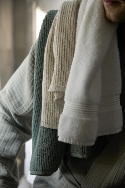 A person with three towels in various colors and textures draped over their shoulder