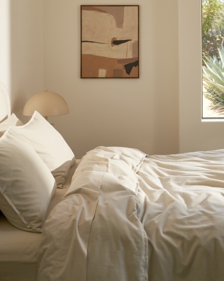 A neatly made bed with bone percale sheets