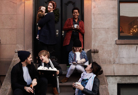 People laughing sitting and standing at the steps of a house. 