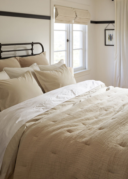 A cozy ivory cotton gauze quilt on a plush bed with white cotton percale sheets