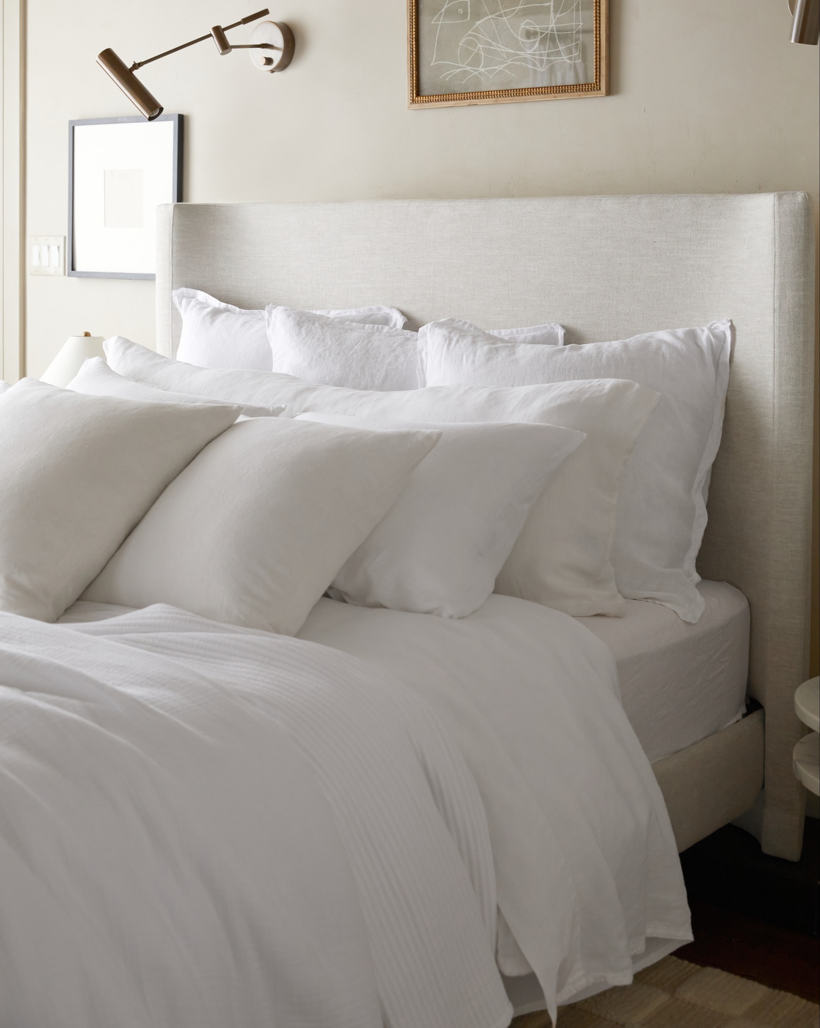 A neat bed with all white bedding and rows of plush pillows