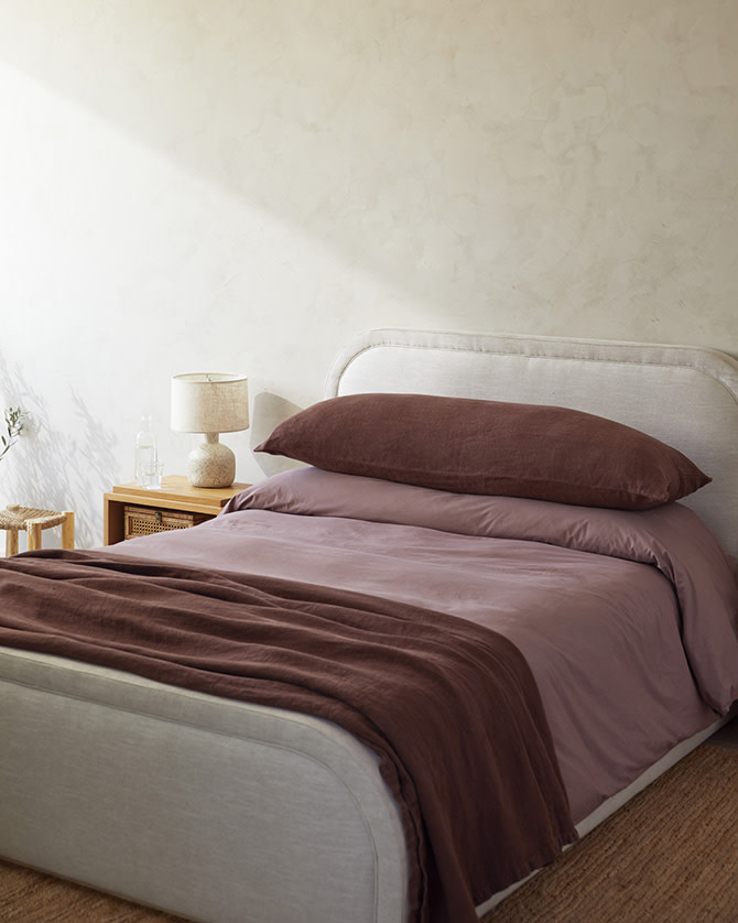 Neatly made bed with light and dark purple bedding