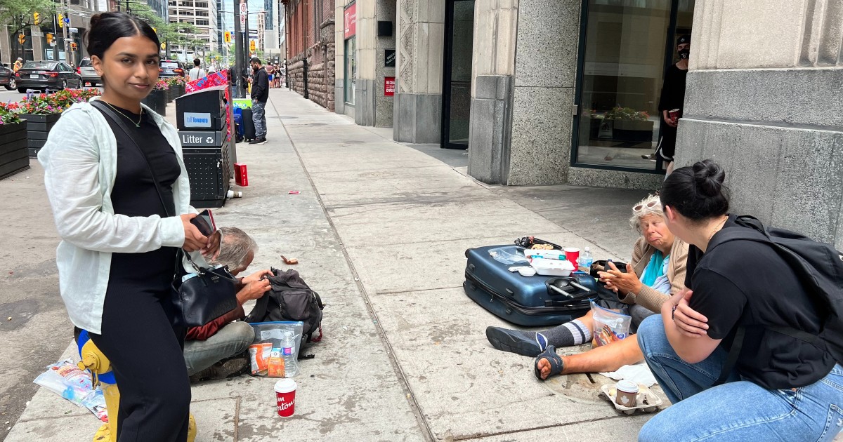 Two members from Blankets for T.O. approach homeless individuals on the street to have a brief conversation and make a donation.