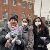 Members from Blankets for T.O. pose with a donation package recipient during a downtown Toronto donation run in December 2021.