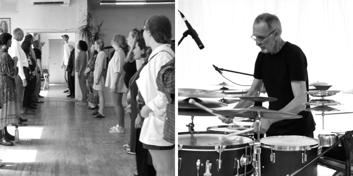 Two lines of people face each other, mouths open singing. Man surrounded by cymbals and drums against a white backdrop.