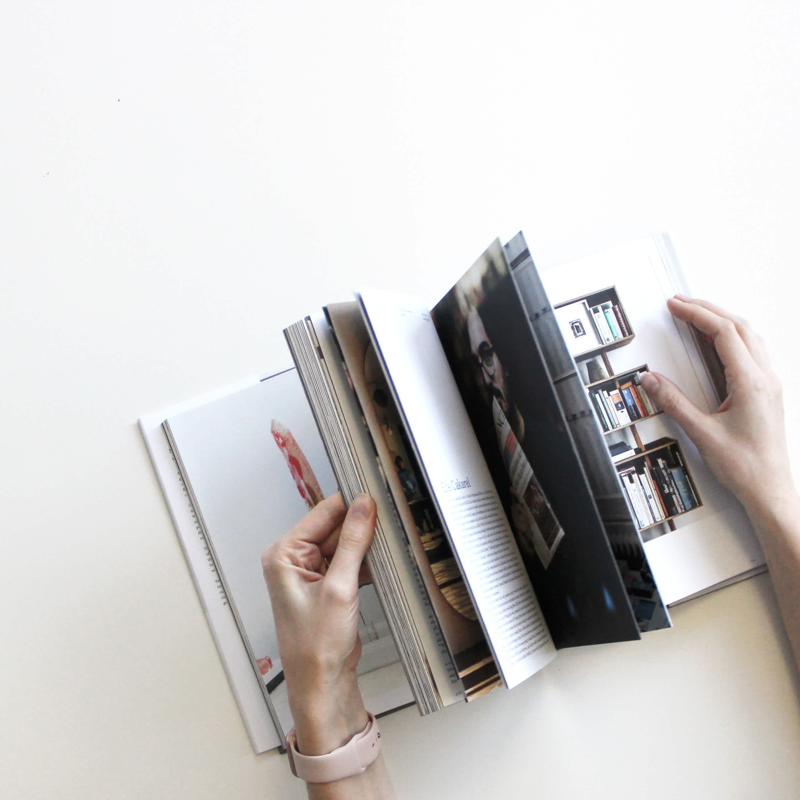 A person flipping through a design book with large photography.
