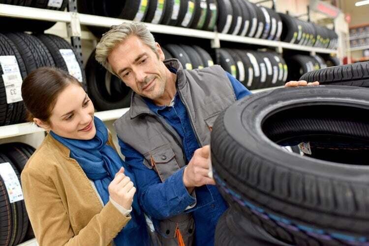 A woman and a store representative are looking at tires.