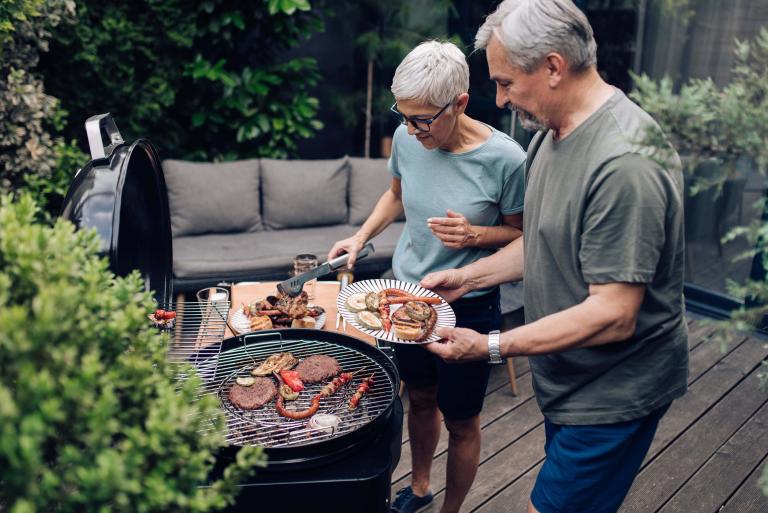 An older couple grilling on their patio outdoors