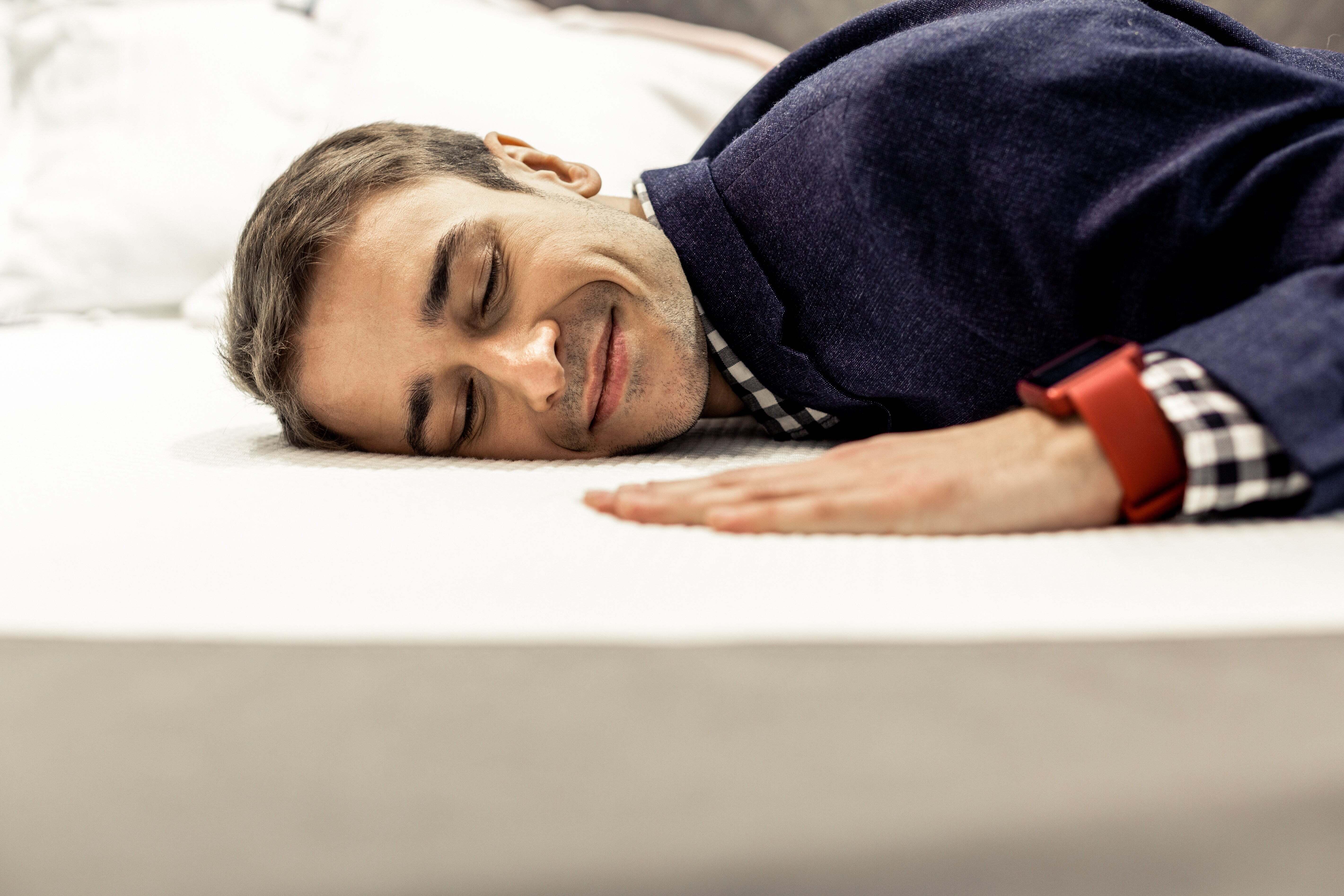 A man laying on a mattress smiling