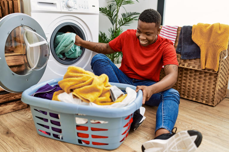 A young adult unloading a dryer, showing the ease of using a washer and dryer he got with the help of an Acima Leasing retailer.