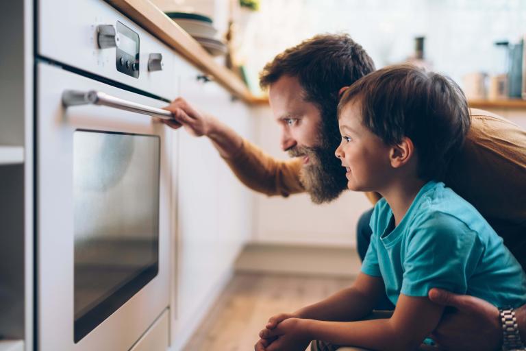 A man and a boy looking at what's inside an oven