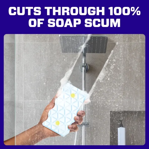 Hand holding a Mr. Clean Magic Eraser under a showerhead, demonstrating effective removal of soap scum