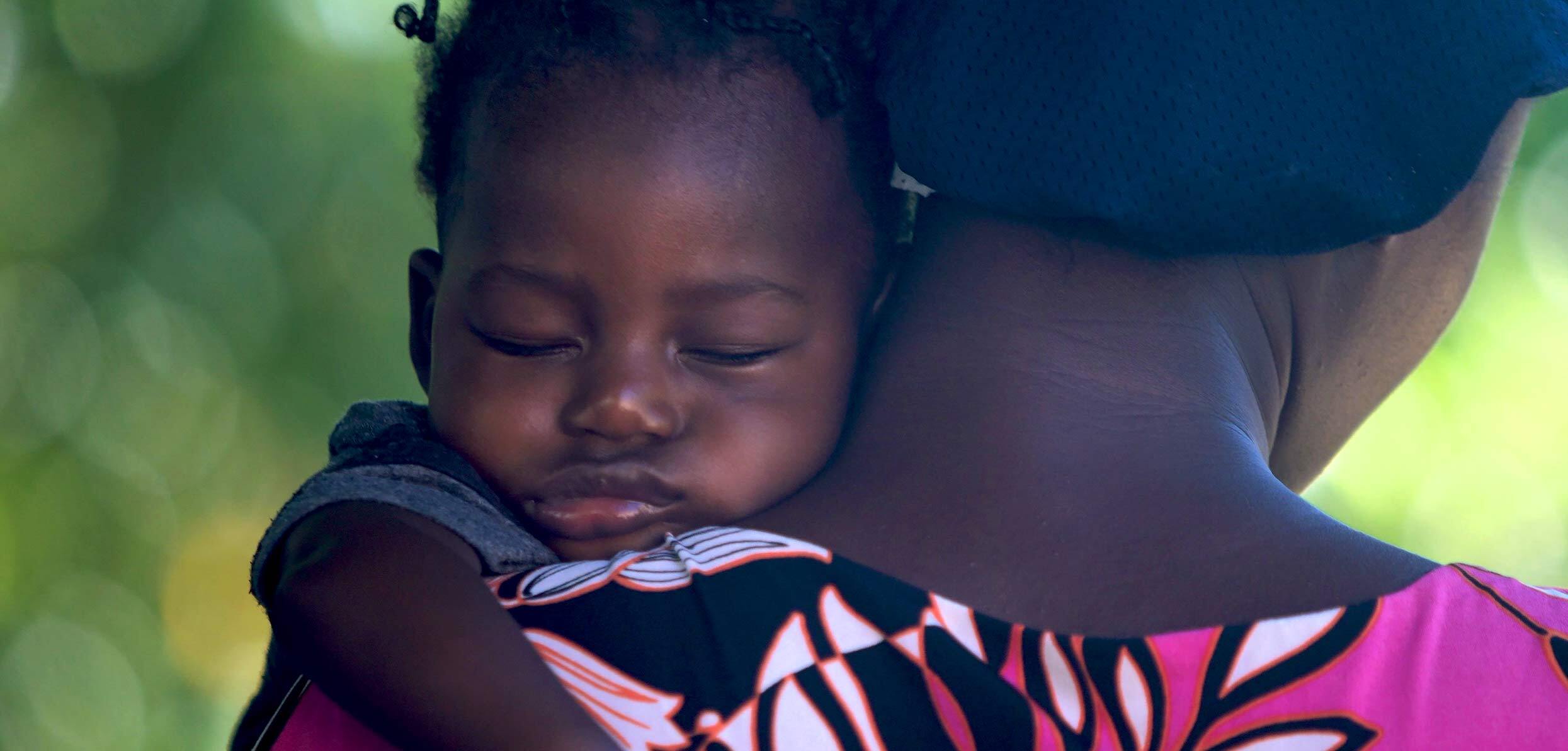 sleeping baby carried by her mother