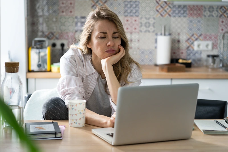 Tired woman reading article on laptop.