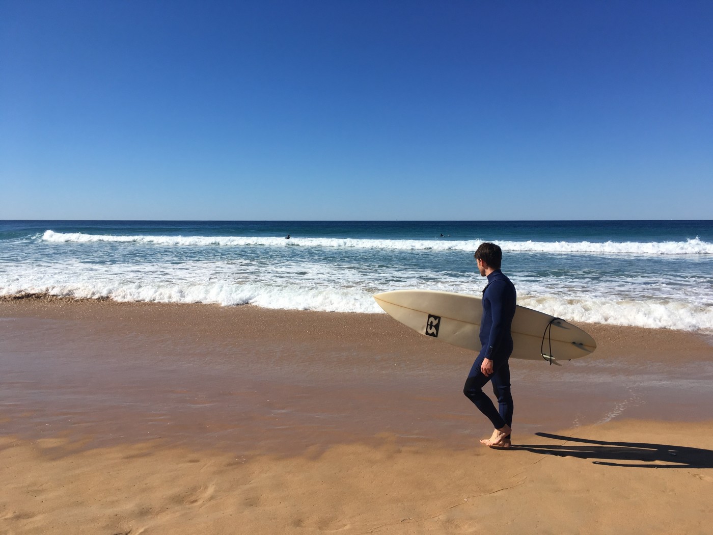 Chris on the beach with a surfboard