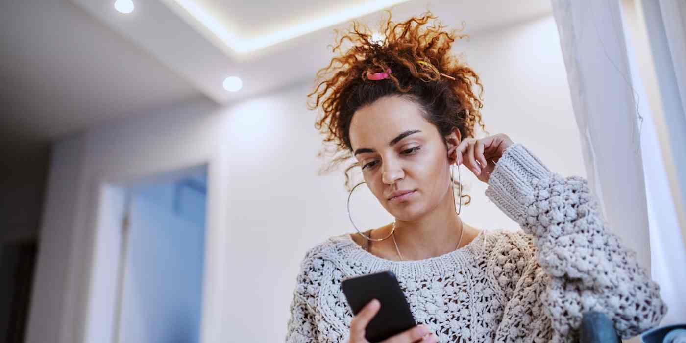 Hero image of a woman with a comfy sweater looking at her phone