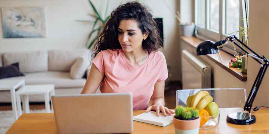 Hero image of a woman at a computer with a notepad