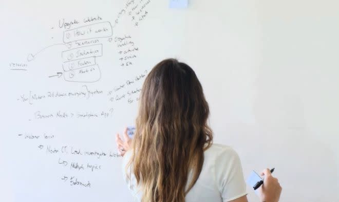 A stock image of a woman writing on a whiteboard