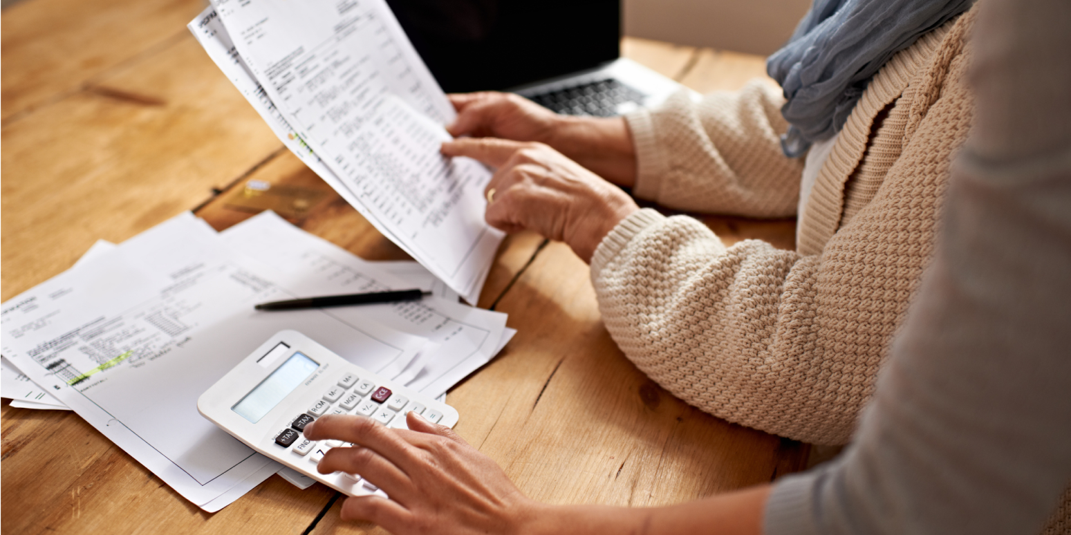 Hero image with the arms and hands of two people looking over financial documents, with a calculator