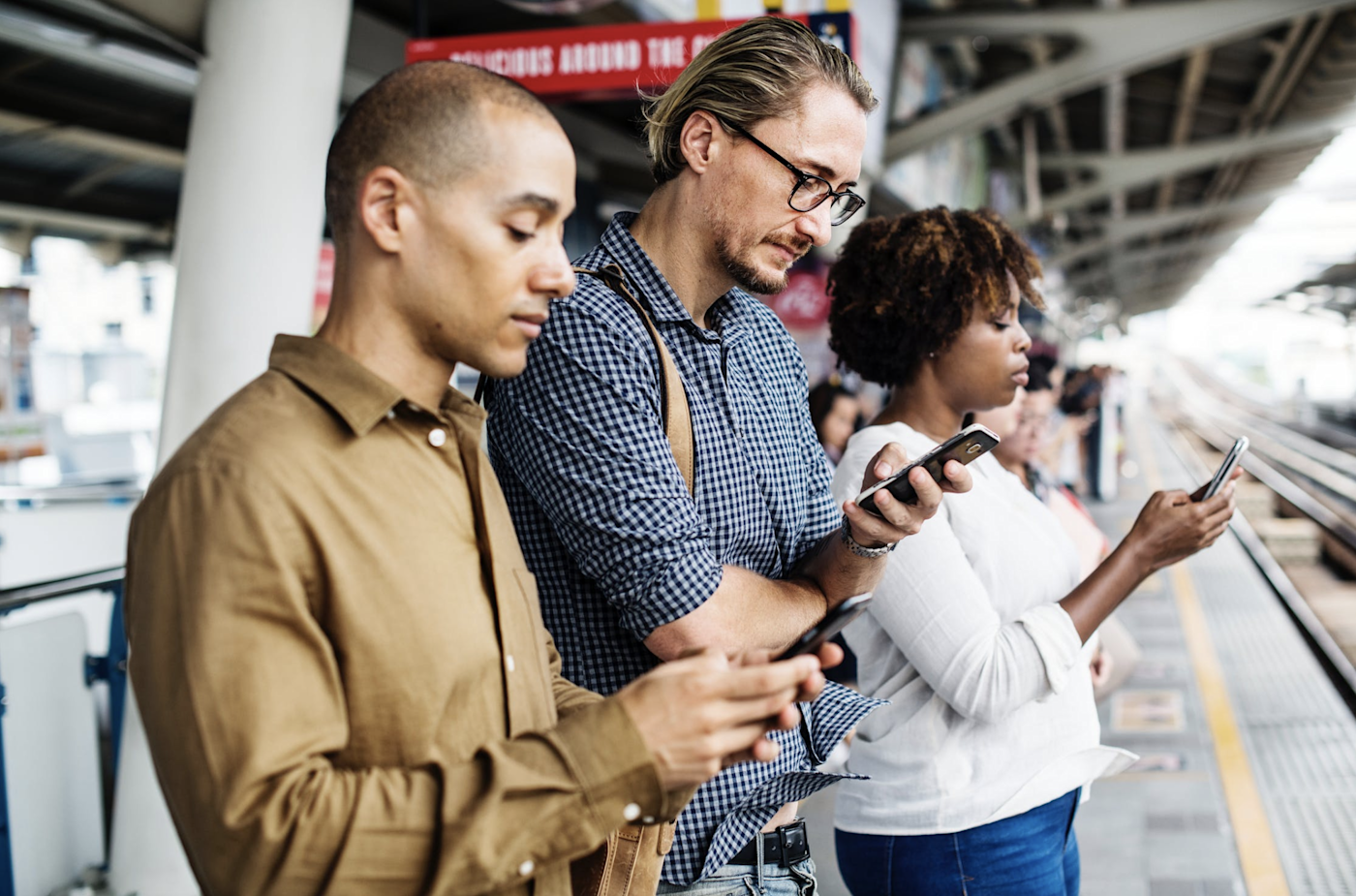 People looking at their phones while waiting for the subway