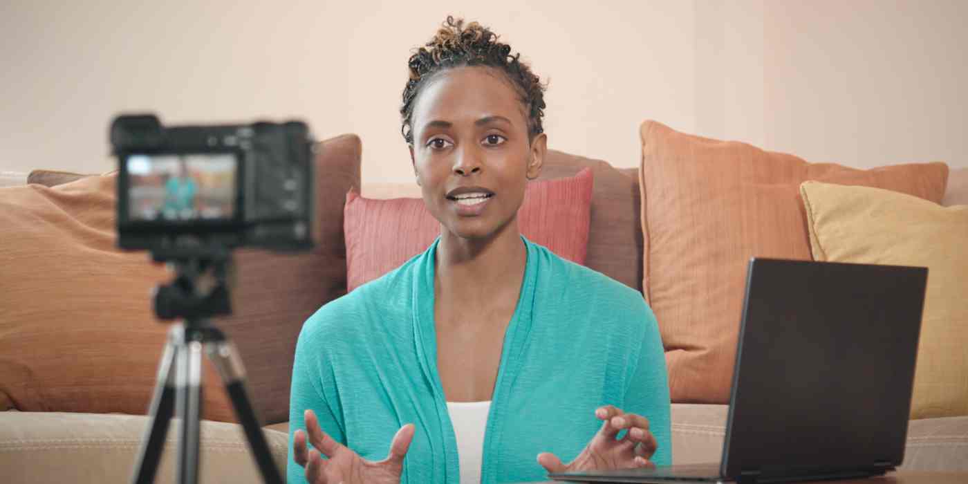 Hero image of a woman talking to a camera with a computer next to her