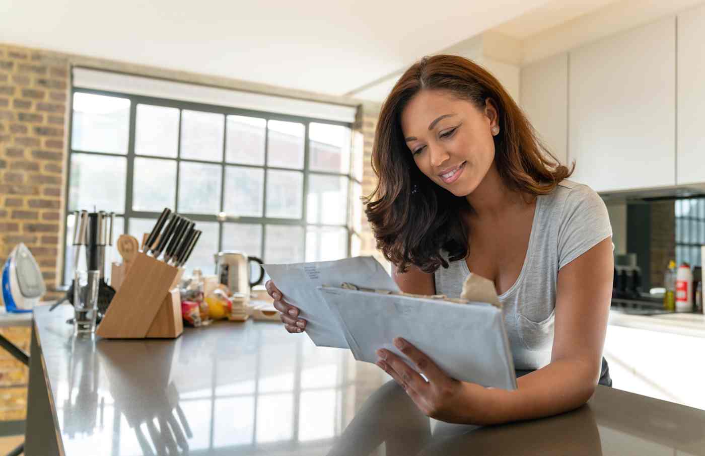 A woman in a kitchen reading the mail