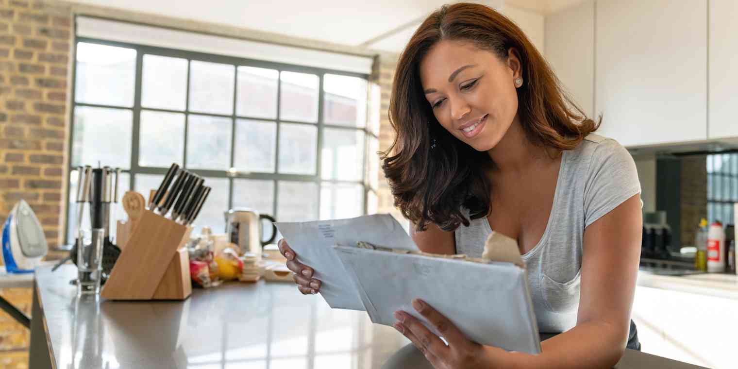 A woman in a kitchen reading the mail