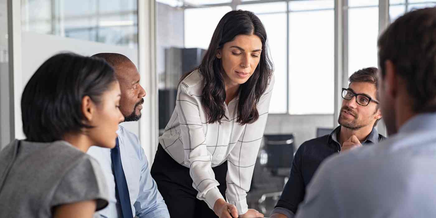 Hero image of a woman looking over a table with four other people looking at her